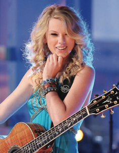 a woman with long blonde hair and a blue dress holding a guitar in her hand