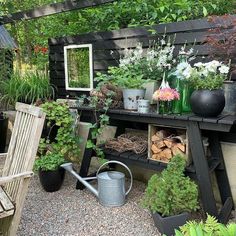 an outdoor garden area with potted plants and gardening tools on the table, surrounded by wooden slats