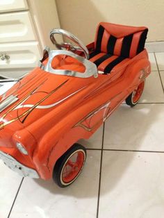 an orange toy car sitting on top of a tiled floor