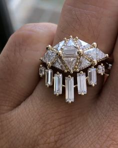 a woman's hand with a ring on it that has three stones in the middle