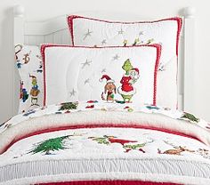 a white bed topped with lots of pillows and comforter covered in christmas themed sheets