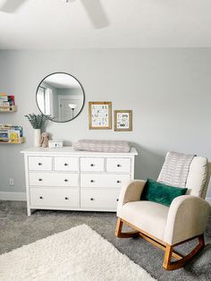 a baby's room with a rocking chair, dresser and mirror on the wall