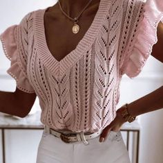 a woman wearing white pants and a pink sweater