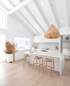 a large open kitchen with white walls and wood flooring that has an island in the middle