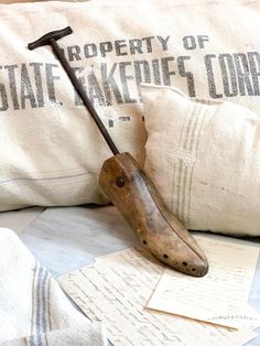 an old wooden mallet laying on top of a pillow next to some postcards