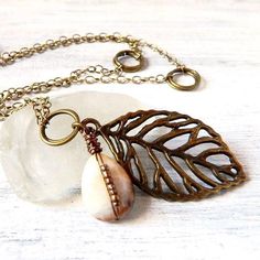 You'll receive this lovely woodland inspired rustic patina leaf necklace features natural antique brass gold leaf branch pendant.   A rugged looking briolette gemstone cream jasper pendant with hints of brown drops alongside the leaf.   In this long bohemian stone necklace, I hand wire wrapped the neutral tone jasper teardrop in antique bronze, and set tiny bronze glass seed beads floating along the wire in the front.   All suspends from high quality hypoallergenic electroplated soldered antique brass gold chain, with large double rings set along the chain, and fastens with antique brass gold lobster claw.   Earthy warm hues in a boho chic long layered look. . . .  ⚜️ Chain Length : shown 24" inches long  ⚜️ Leaf Pendant : drops 2 inches down from the chain  ⚜️ Antique Brass Leaf Charm : Bohemian Brass Leaf Jewelry, Bohemian Leaf-shaped Brass Jewelry, Bohemian Brass Teardrop Pendant Jewelry, Bohemian Leaf-shaped Metal Jewelry, Nature-inspired Bronze Jewelry With Natural Stones, Bohemian Teardrop Pendant Copper Necklace, Bohemian Copper Teardrop Pendant Necklace, Bohemian Gold Leaf Jewelry, Nature-inspired Leaf Shaped Brass Jewelry