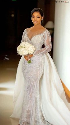 a woman in a wedding dress holding a bouquet and posing for the camera with her hands on her hips