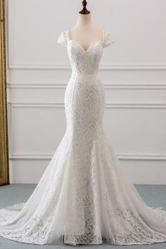 a white wedding dress on a mannequin in front of a gold framed mirror