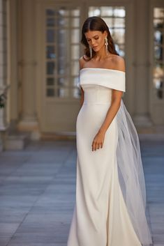 a woman in a white dress and veil posing for the camera with her hand on her hip