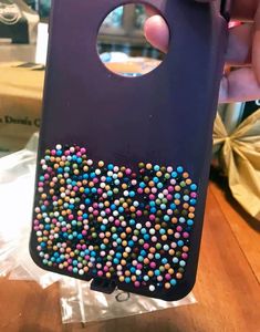 someone is holding up their phone case with colorful beads on the front and back cover