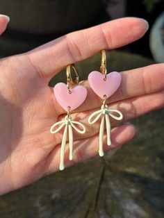 Pink heart resin earrings with cream coloured bows, hung on gold plated huggies Cute Earrings With Pink Bow For Gift, Heart-shaped Earrings With Bow For Gift, Cute Pink Bow Earrings As Gift, Cute Pink Bow Earrings For Gift, Party Heart Earrings With Bow, Heart Shaped Bow Earrings For Party, Valentine's Day Gift Jewelry With Pink Bow, Heart-shaped Bow Jewelry Gift, Heart Shaped Bow Jewelry For Gift