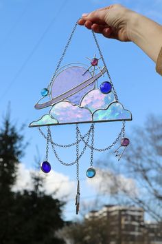 a hand holding up a stained glass sun catcher with planets and stars on the side