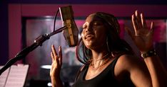 a woman singing into a microphone with her hands in the air and music notes behind her