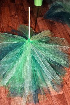 a green tulle skirt sitting on top of a wooden floor next to a cup