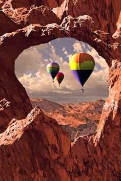 there are two hot air balloons flying in the sky above some rocks and dirt,