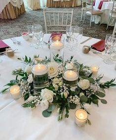 a centerpiece with candles and flowers on a table in a banquet or wedding reception