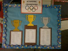 a bulletin board with three trophies and the olympic logo on it for kids to play in