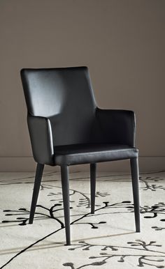 a black leather chair sitting on top of a white rug in front of a wall