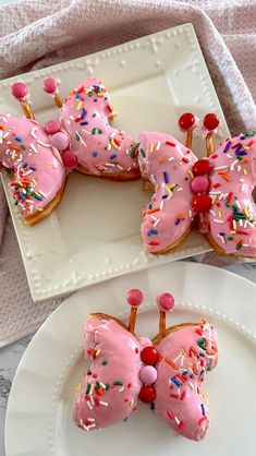 pink frosted doughnuts with sprinkles and bows on them sitting on a white plate