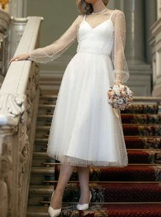 a woman in a white dress standing on some stairs