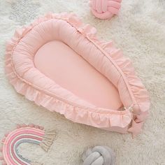 there is a pink baby bed and toys on the floor in front of it,