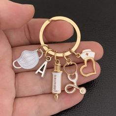 a hand holding a gold keychain with medical items on it