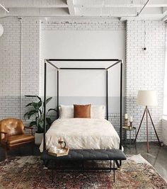 a bedroom with a bed, chair and rug in front of a brick wall on the floor