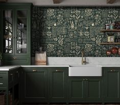 a kitchen with green cabinets and wallpaper in the back ground, along with a white sink