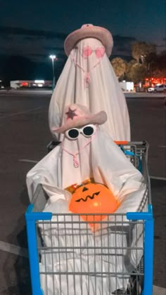 a shopping cart with a costume on it and some pumpkins in the basket next to it