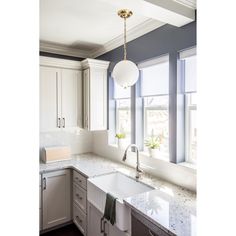 a kitchen with marble counter tops and white cabinets, along with two windows that look out onto the street