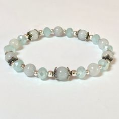 This genuine Aquamarine bracelet is 8" It is created with 8mm natural Aquamarine beads which are selected to match as best possible. To add a little sparkle are glass crystal faceted beads and silver filigree end caps.  Aquamarine is a stone of courage with calming energy to reduce life's stress and bring quiet to the mind.  Helps you connect with your inner-self and intuition. 🌹 Each piece of jewelry will come to you with the name of your stone and a brief description of the healing energy it Silver Beaded Bracelets For Healing, Healing Silver Beaded Bracelets With Faceted Beads, Silver Hypoallergenic Stretch Bracelet For Healing, Silver Jade Beaded Bracelets With Gemstone Beads, Silver Hypoallergenic Stretch Bracelet, Silver Jade Beaded Bracelet With Natural Stones, Silver Jade Beaded Bracelets With Natural Stones, Silver Jade Beaded Bracelets With Gemstones, Silver Jade Beaded Bracelets With Round Beads