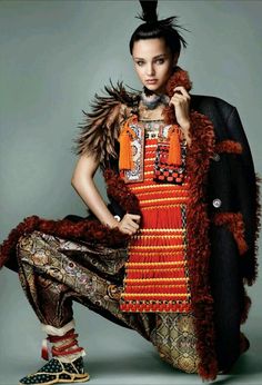 a woman in an orange and black dress with feathers on her head is posing for the camera