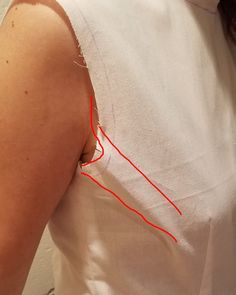 a woman wearing a white shirt with red thread on it