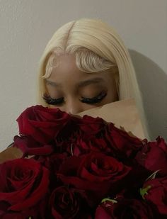 a woman hiding her face behind a bouquet of red roses with long hair and black eyeliners