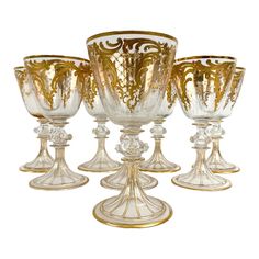 four glass goblets with gold designs on them