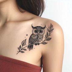 an owl tattoo on the back of a woman's upper arm, with leaves and stars