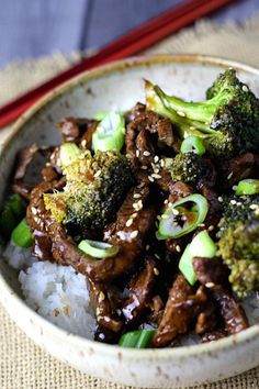 a bowl filled with beef and broccoli on top of rice