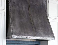 a large metal oven hood mounted on the side of a kitchen wall above a stove