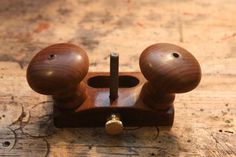 two wooden knobs are attached to the handle of a woodworking machine, which is on top of a piece of plywood