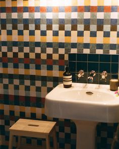 a bathroom sink sitting under a mirror next to a tiled wall