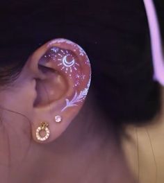 a close up of a person's ear with glow in the dark designs on it