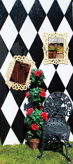 a black and white checkered wall with a chair, potted plant and pictures on the wall