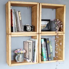 three wooden shelves with books and flowers in them on the wall next to each other