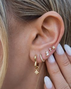 a close up of a woman's ear with gold stars and moon piercings