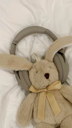 a stuffed animal with headphones on it's ears laying on a white sheet