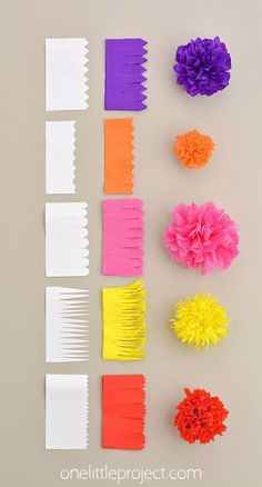 several different types of paper flowers are arranged on a table with white and orange strips