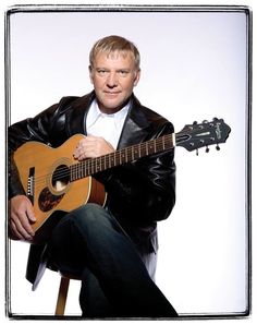 a man holding a guitar in his right hand