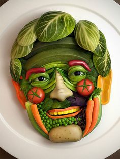 a face made out of vegetables on top of a white plate