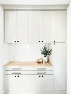 a kitchen with white cabinets and wooden counter tops