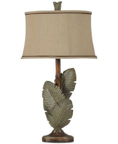 a table lamp with a beige shade on it and a green leaf design in the middle